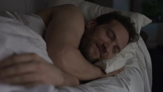 Male in bed smiling before falling asleep, pleasant thoughts positive experience
