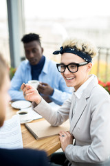 Cheerful young employee laughing during conversation with colleague about plans for new working year