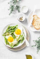 Healthy breakfast or snack - a fried egg with green beans on a light background, top view