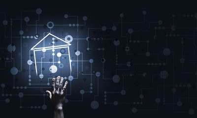 Conceptual image with hand pointing at house or main page icon on dark background