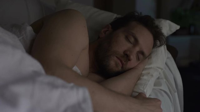 Adult bearded man sleeping in bed, exhausting day, sound sleep and night rest