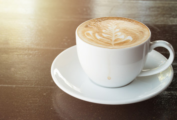 Cup of coffee with latte art on wooden table background