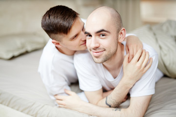 Fototapeta premium Young affectionate homosexual guys lying in bed and enjoying spending time together