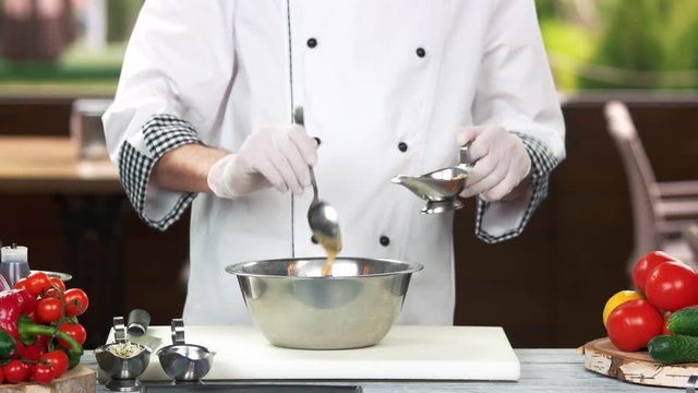 Chef with spoon adding sauce. Kitchen, food preparation.