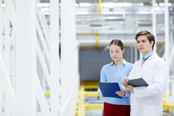 Obraz premium Young IT-service engineers describing characteristics of new technical equipment or hardware in mining farm