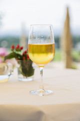 One wineglass with white wine on table with tablecloth