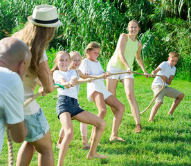 people with kids having fun outdoors pulling rope