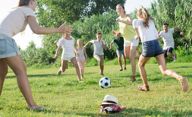 Group of happy people with children outdoors playing football