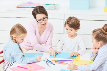 Young teacher explaining little boy how to draw and what to start with
