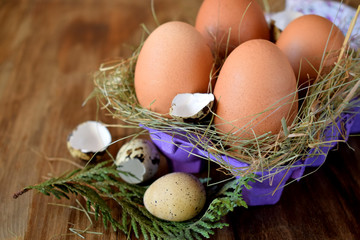 Chicken and quail eggs in a carton box on a wooden table
