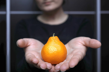 Woman holding fresh tangerine. Unusual tropical fruit looks like pear.