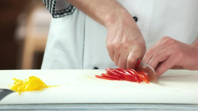 Hands cutting red paprika. Pieces of bell pepper.