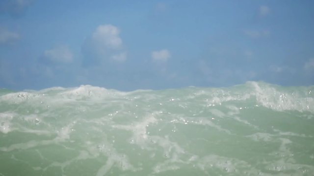 Young handsome man swimming in the sea and splashing giant wave in slow motion. 1920x1080
