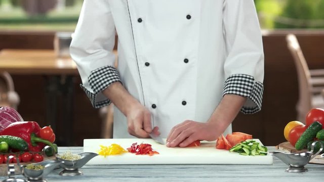 Chef cutting tomato. Pieces of fresh vegetables.