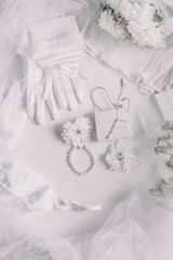 White bridal accessories for wedding background with pearls, white satin ribbons and lace, gloves, bracelet,flat lay for fashion blog, top view