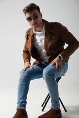 young man wearing sunglasses and leather jacket sitting