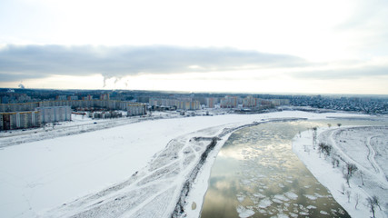 Ice swims in the river. Winter landscape photographed from above near the city. Top view. Nature and abstract background