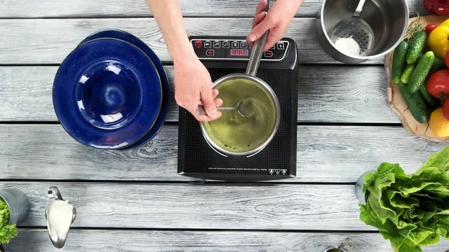 Hands cooking soup. Vegetable puree in saucepan.
