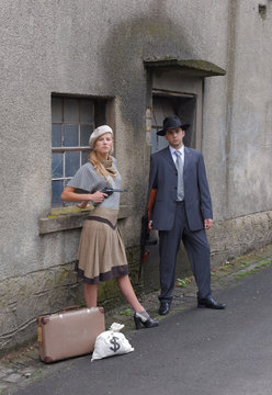 Two models get dressed up in 1930's style  vintage fashion clothes and act the role of  the gangster duo Bonnie and Clyde.