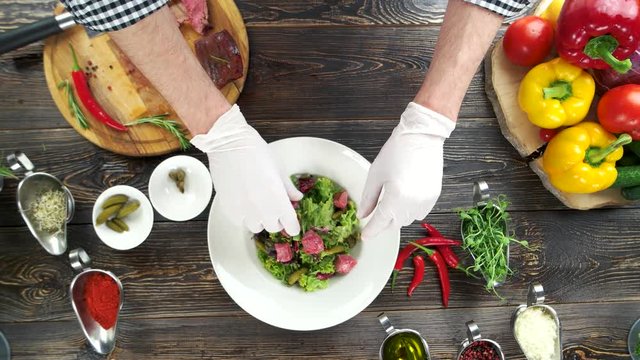 Beef salad preparation. Kitchen table, male hands.