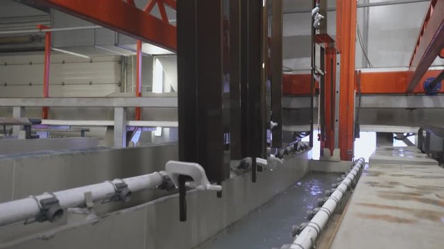 Manufacture. Process of anodizing aluminum plates in production, Immersion of aluminum plates in liquid. Automatic production line.
