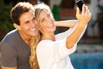 Close up couple sitting together by pool taking selfie