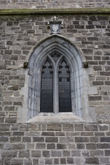 Arched gothic double church window with multiple glass panes in stone frame.