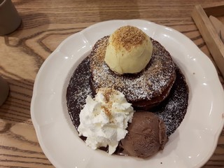 Ice Cream Vanilla, placed on a chocolate cake. Sprinkle with icing sugar, Decorate with whipped cream , Ice Cream Flavor Chocolate. Arranged on a white dish beautifully. on a wooden table