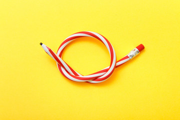 Flexible pencil on a yellow background. Bent pencils two-color
