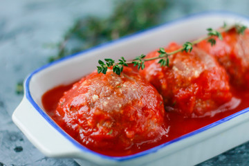 Raw meatballs from beef in tomato sauce with thyme