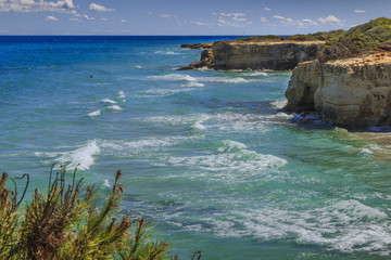 The most beautiful coast of Apulia: Torre Sant'Andrea, ITALY.Typical coastline of Salento:  seascape with cliffs, rocky arch and sea stacks (faraglioni).Summertime:in the distance bathers in the wave.