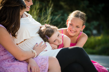 Happy pregnant mother with kids outdoor in summer nature