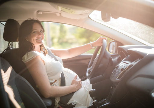 Beautiful smiling pregnant woman sitting in car
