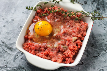 Raw ground beef with chicken egg and spices with thyme