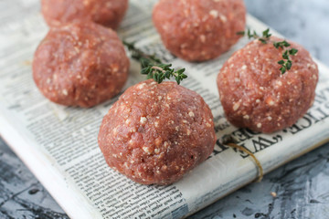 Raw meatballs of beef with thyme on the board
