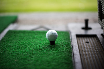 Golf ball on artificial green grass place with tee for practice Driving Range