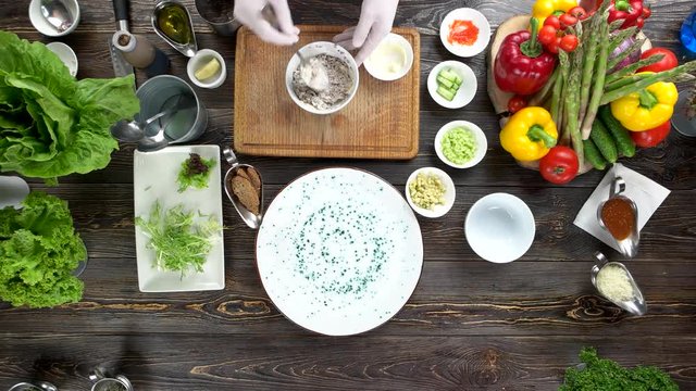 Hands preparing and garnishing food. Herring tartare on the table.