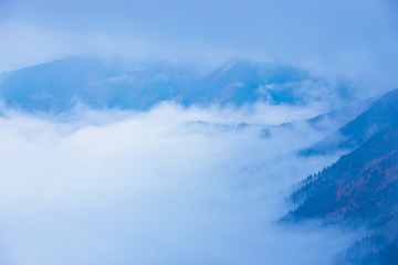 foggy mountain landscape with clouds above the peaks