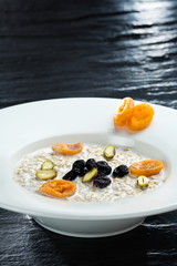 Oatmeal With Dried Fruit vertical close up shot on the dark background