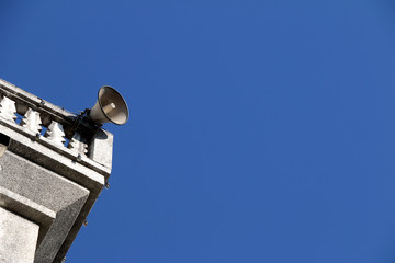 loudspeakers on a rooftop of church on blue sky with copy space
