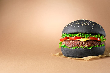 Black burger with beef and cheese isolated on craft paper background. 