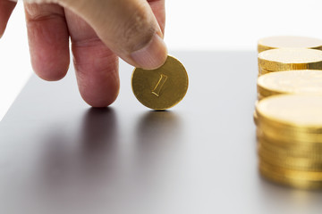 Hand picking up one gold coin