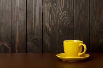 Ceramic cup for coffee and tea of yellow color on a dark wooden background.