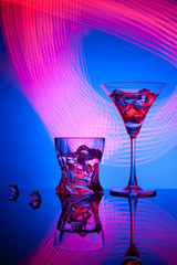 Two glasses a cocktail Martini whisky ice, against the blue background of beautiful light effects.
