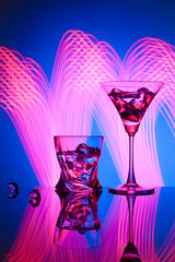 Two glasses a cocktail Martini whisky ice, against the blue background of beautiful light effects.