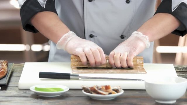 Chef making a sushi roll. Man preparing japanese food.