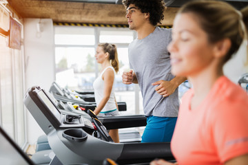 Naklejka na ściany i meble Group of friends exercising on treadmill machine
