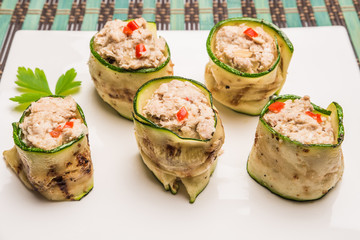 Grilled zucchini rolls with curd cheese and tuna on plate.