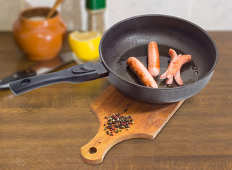 Fried vienna sausages in the frying pan on cook table
