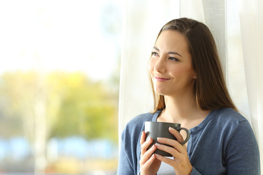 Satisfied woman thinking holding a coffee mug